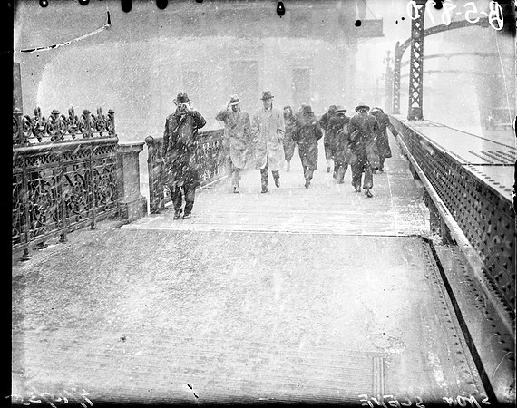 Pedestrians crossing bridge during snowstorm