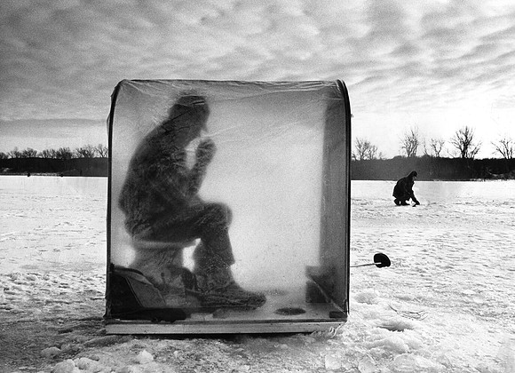 An ice fisherman keeps warm on a small lake (ST-17500920)